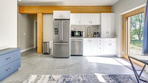 A modern kitchen with stainless steel appliances, white cabinetry, and a wooden ceiling beam. - Unique Grand Junction Guest Suite w/ Gas Fire Pit! (Grand Junction)