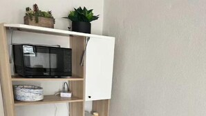 Une petite cuisine équipée comprenant un four à micro-ondes, une cuisinière et des placards blancs.