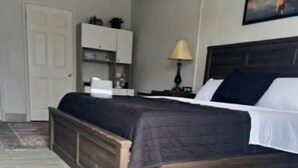 Une chambre à coucher avec un lit, une table de chevet, une lampe, une armoire et une porte.