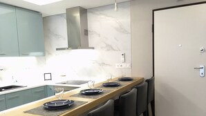 Una cocina moderna con una isla central, armarios grises y una puerta blanca.