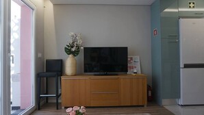 Una sala de estar moderna con televisor de pantalla plana, un mueble de madera y una mesita con flores.