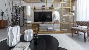 Ein modernes Wohnzimmer mit einer schwarzen Couch, einer weißen Vase und einem Bücherregal.