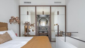 Ein modernes Schlafzimmer mit einem großen Bett, einem Schminktisch mit Spiegel und einem begehbaren Kleiderschrank.