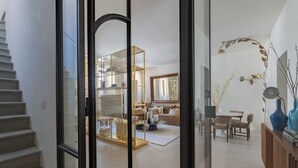 Ein modernes Wohnzimmer mit Glastrennwand, einer Treppe und einem Essbereich mit Tisch und Stühlen.