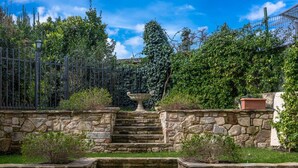Eine Steintreppe führt zu einem Garten mit einer großen Vase am oberen Ende.