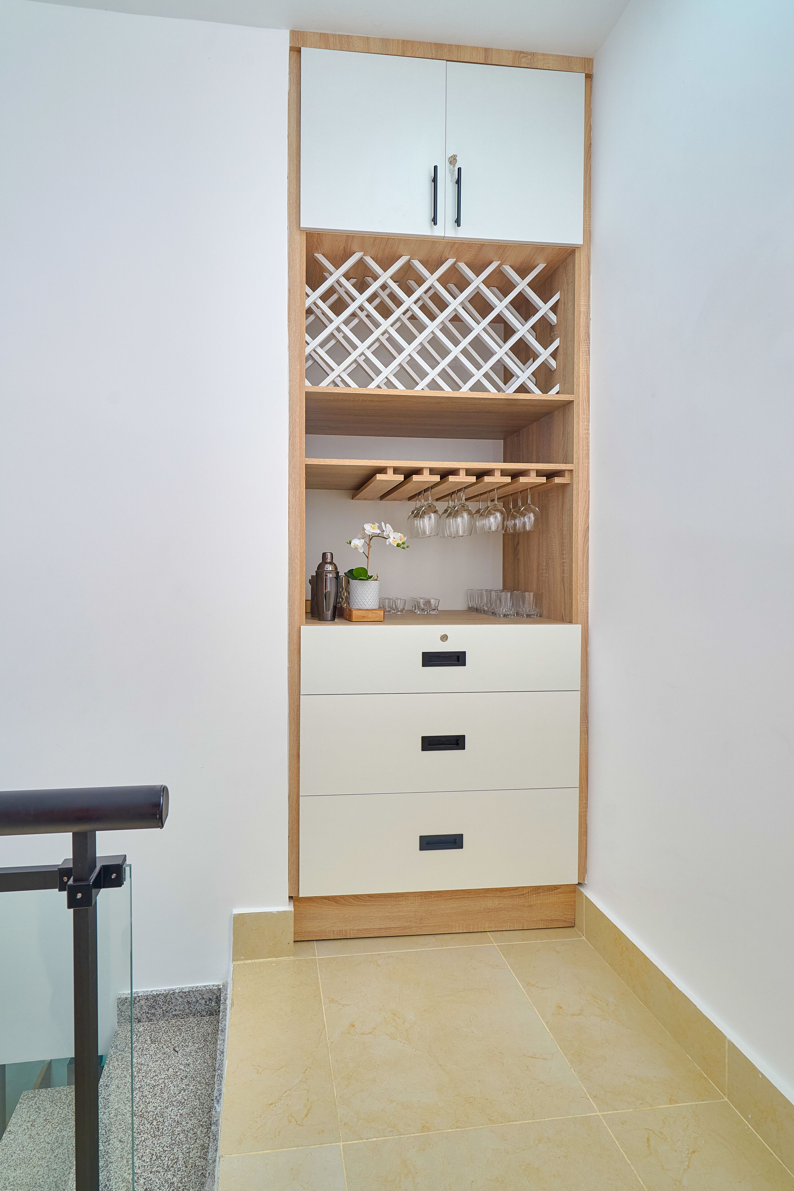A corner room with a white cabinet, a wine rack, and a small plant.