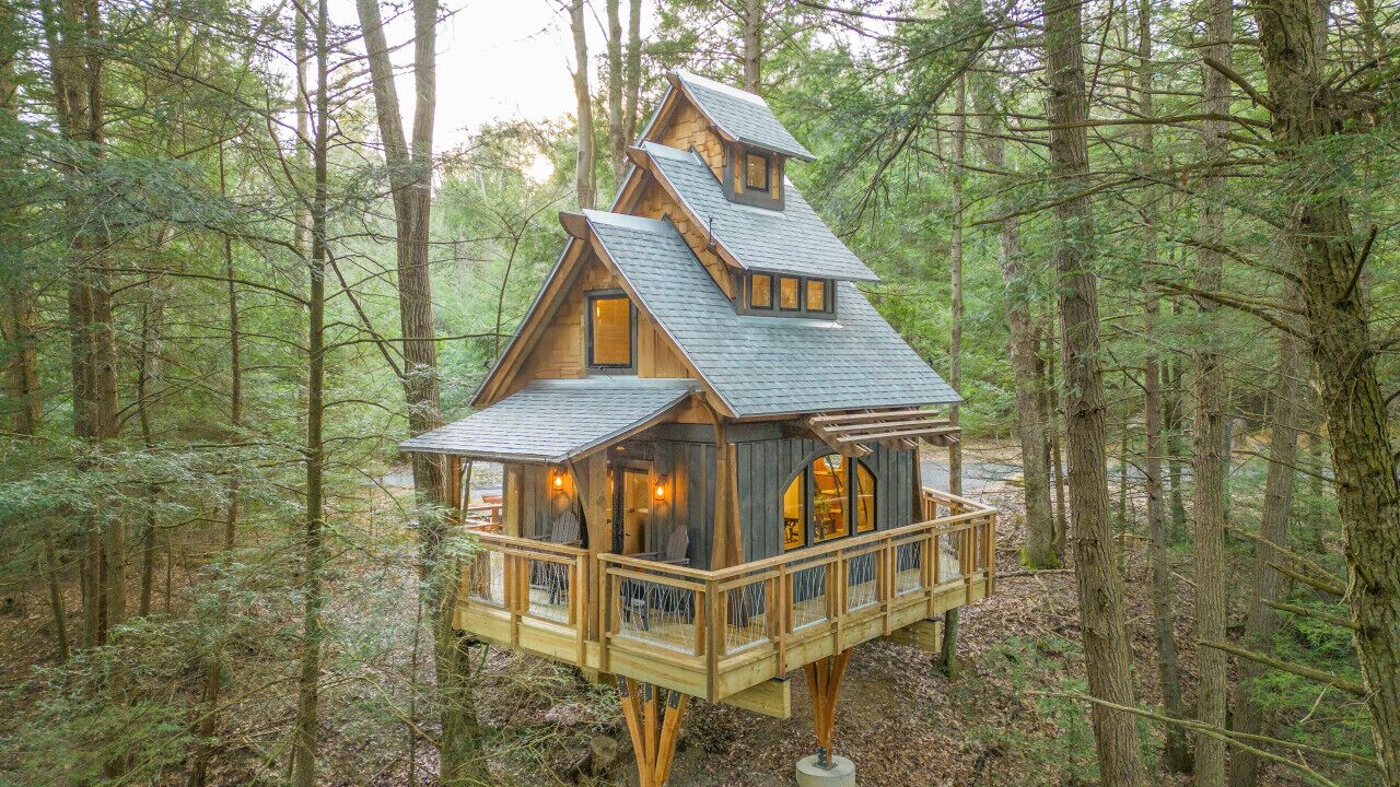 A wooden cabin with a balcony, surrounded by a forest.