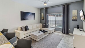 Ein modernes Wohnzimmer mit einem Ecksofa, einem Couchtisch, einem Flachbildfernseher und Kunstwerken an den Wänden.