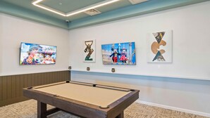 Une table de billard dans une pièce où sont accrochées quatre œuvres d’art encadrées au mur.