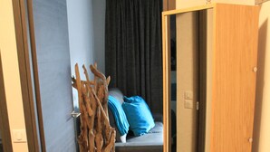 Una habitación con una cama, una cortina oscura, una escultura de madera y un espejo.