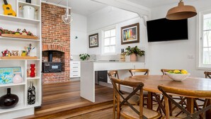 Cozinha com parede de tijolos, piso de madeira e um espaço de jantar com mesa e cadeiras.