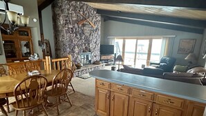 A spacious kitchen with a stone accent wall, wooden cabinetry, and a large dining table with chairs.