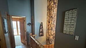 A wooden staircase with a stone accent wall and a sign listing lake rules.