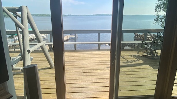 A room with a large window overlooking a wooden deck and a body of water.