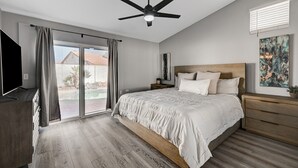 A bedroom with a bed, a ceiling fan, a TV, a window with curtains, and a painting on the wall. - Entire Home in Las Vegas! (Las Vegas)