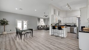 A spacious living area with a dining table and chairs, a kitchen with white cabinets, and a ceiling fan. - Entire Home in Las Vegas! (Las Vegas)
