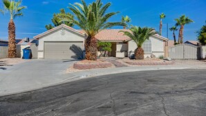 A single-story house with a garage, surrounded by palm trees and a paved driveway. - Entire Home in Las Vegas! (Las Vegas)