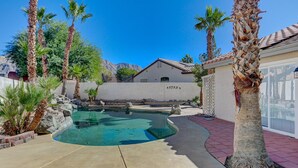 A swimming pool with a curved design, surrounded by palm trees and a house with a tiled roof. - Entire Home in Las Vegas! (Las Vegas)