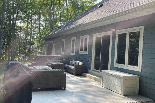 Un patio techado al aire libre con muebles de mimbre y una parrilla.