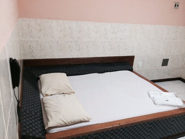 A single bed with a wooden frame, a white mattress, and a beige pillow. - Pousada Acrópole (Belém)