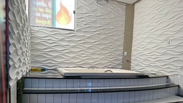 A modern bathroom with a textured wall, a bathtub, and a tiled floor. - Pousada Acrópole (Belém)