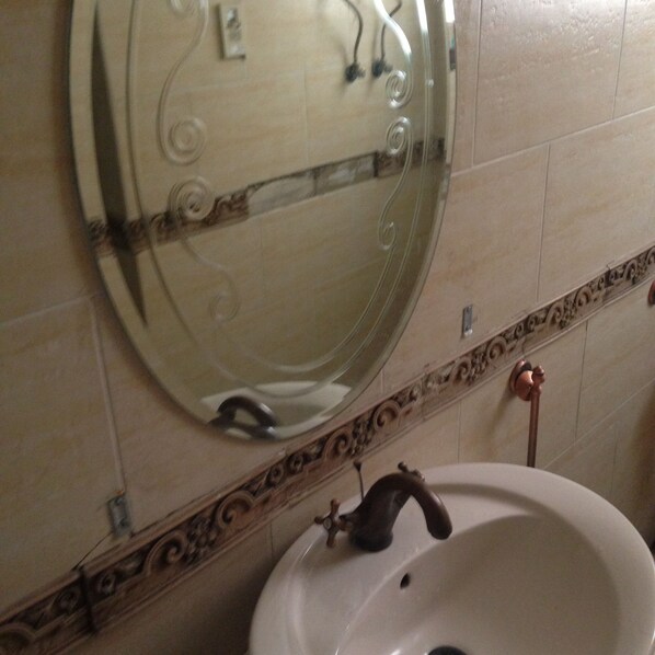 A bathroom with a round mirror, a sink, and a decorative tile border. - Central, Fully Equipped, 3 BR flat in Best Spot in Mohandssen area, Cairo (Giza Governorate)