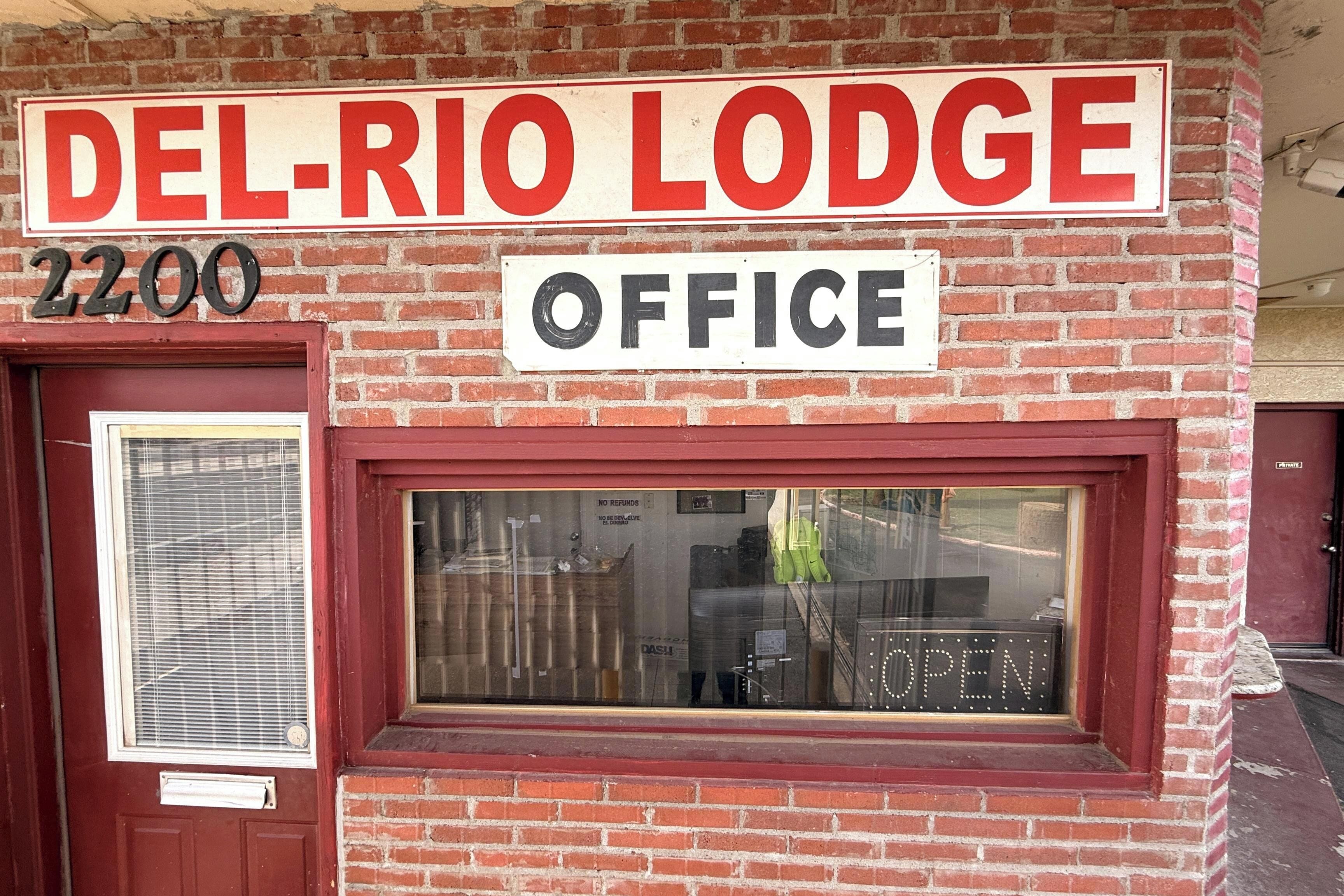 Tiilestä rakennettu rakennus, jossa on kyltti, jossa lukee »DEL-RIO LODGE OFFICE», ja ikkunassa on valaistu teksti »AVOIN».