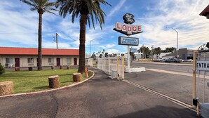 A motel named 'Del Rio Lodge' with a red-tiled roof, palm trees, and a fenced parking area. - Del Rio Hotel O near Mesa Downtown (Mesa)