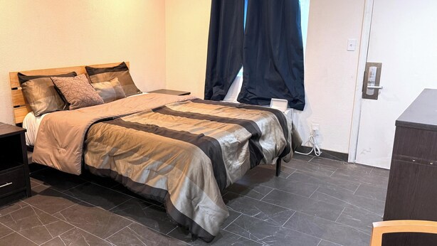 A bedroom with a bed, a nightstand, a dresser, and a window with curtains. - Del Rio Hotel O near Mesa Downtown (Mesa)