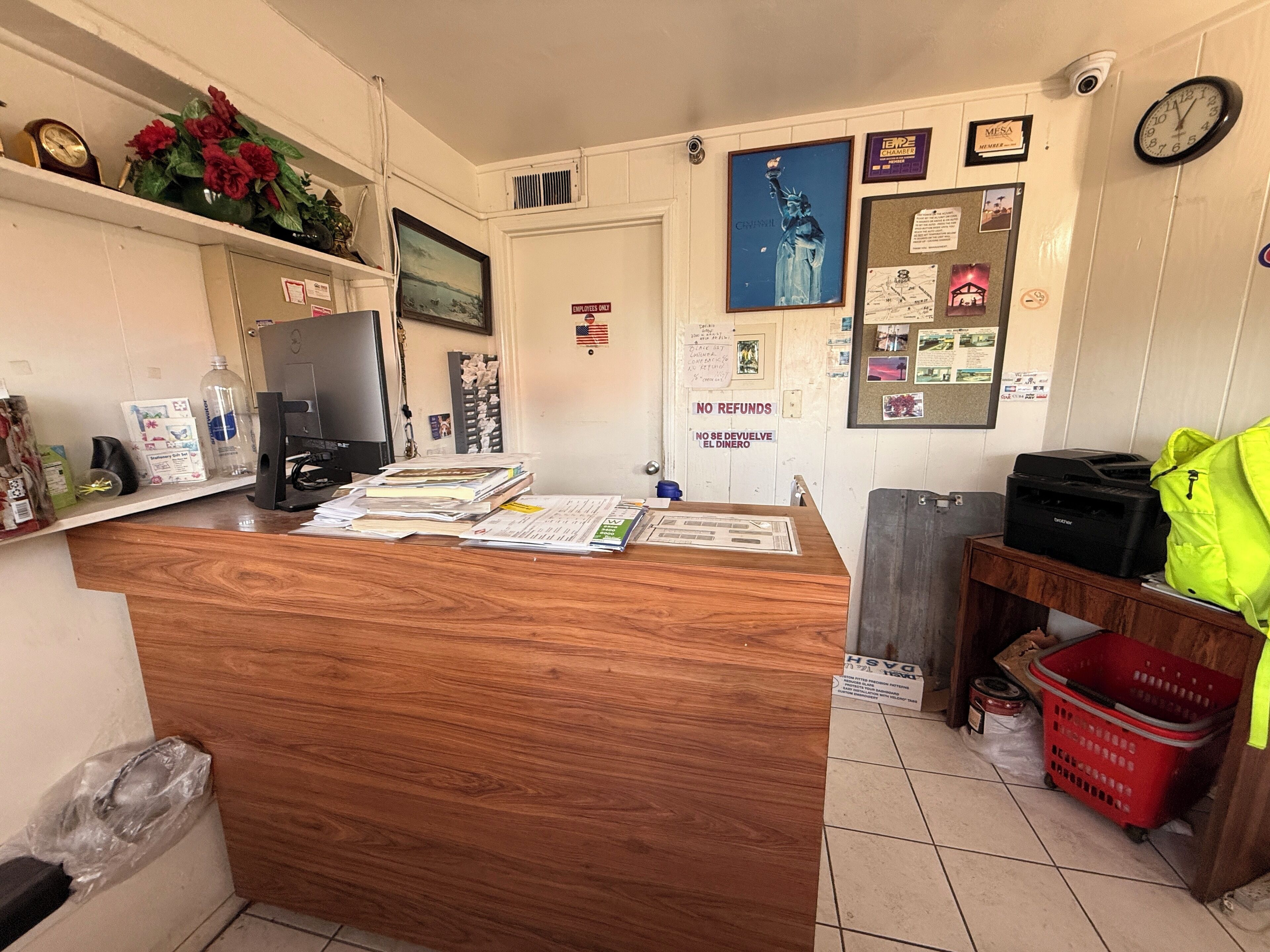 Un comptoir d’accueil avec des documents, une horloge et un panneau d’affichage où sont accrochées diverses annonces.
