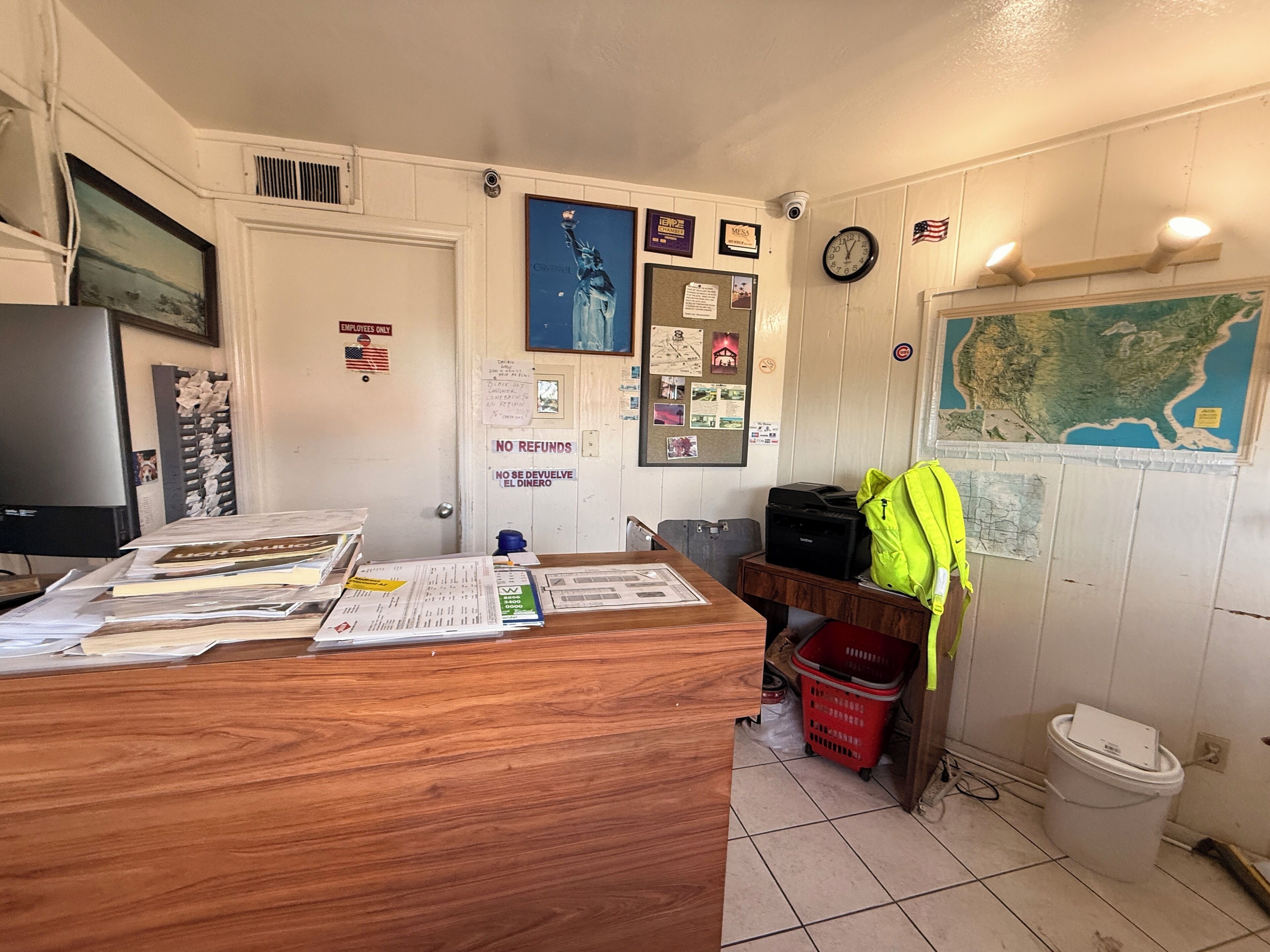 A reception desk cluttered with papers and a bright green backpack.