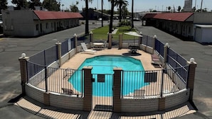 A swimming pool with a surrounding fence, palm trees, and a clear blue sky. - Del Rio Hotel O near Mesa Downtown (Mesa)
