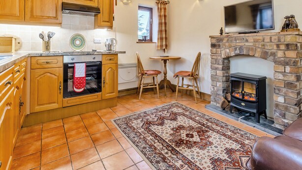 A kitchen with wooden cabinets, a stove, and a dining area with chairs.