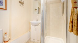 Een badkamer met een douche, wastafel en toilet.