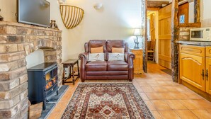 A living room with a fireplace, leather sofa, and a patterned rug.