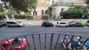 A street view with parked cars and a building with classical architecture. - MANSIONS CENTER LECCE 1 (LECCE)