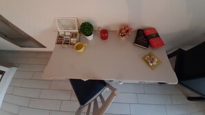 A table with a coffee maker, a yellow mug, a red candle, a small plant, a book, and a plate of cookies. - MANSIONS CENTER LECCE 1 (LECCE)