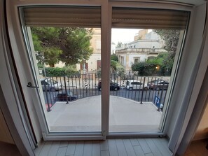 A view from a balcony with a metal railing, a street with parked cars, and buildings in the background. - DWELLING CENTER LECCE - FIVE ROOMS 2 (Lecce)