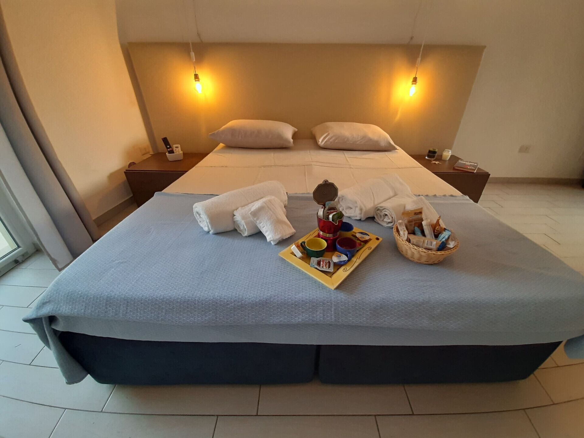 A hotel room with a large bed, two bedside tables, and a tray with breakfast items.