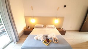 Une chambre d’hôtel avec un grand lit, deux tables de chevet, une petite table et une fenêtre donnant sur la rue.