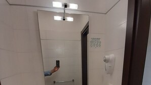Een moderne badkamer met een witte wastafel, een spiegel, een haardroger en een handdoekhouder.
