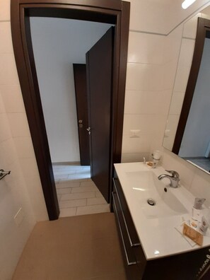 Casa de banho com uma pia branca, um espelho e uma porta de madeira escura.