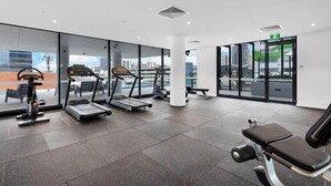 Une salle de sport moderne équipée de tapis de course, d’appareils de musculation et d’un banc.
