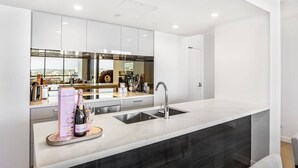 Une cuisine moderne dotée d’un grand îlot central, d’appareils électroménagers en acier inoxydable et offrant une vue sur la ville.