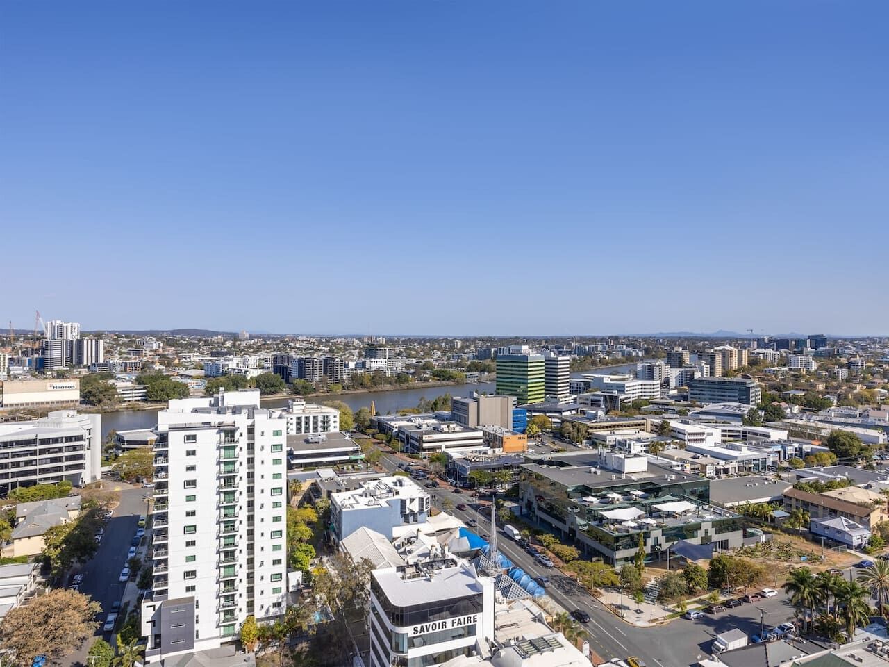A cityscape with a river, modern buildings, and a prominent white building with "Savoir Faire" signage.
