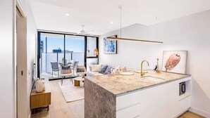 A modern kitchen with a large island, white cabinetry, and a view to the outside. - Conveniently located 2BR apt w/ rooftop pool @Milt (Milton)