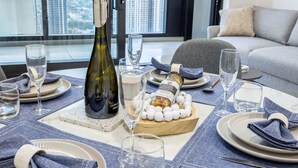 Une table à manger dressée avec des assiettes, des verres, une bouteille de vin et une bouteille de liqueur.