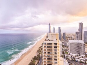 A coastal cityscape with high-rise buildings, a beach, and a clear sky.
