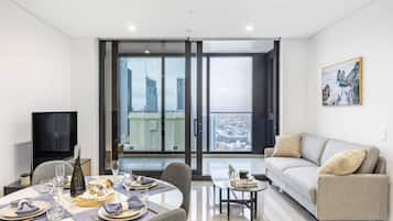 A modern living room with a dining area, a sofa, and a television.