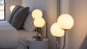 Une chambre moderne avec un lit, deux tables de chevet dotées de lampes sphériques et une fenêtre.